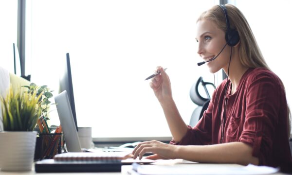 mulher falando ao telefone em frente ao computador